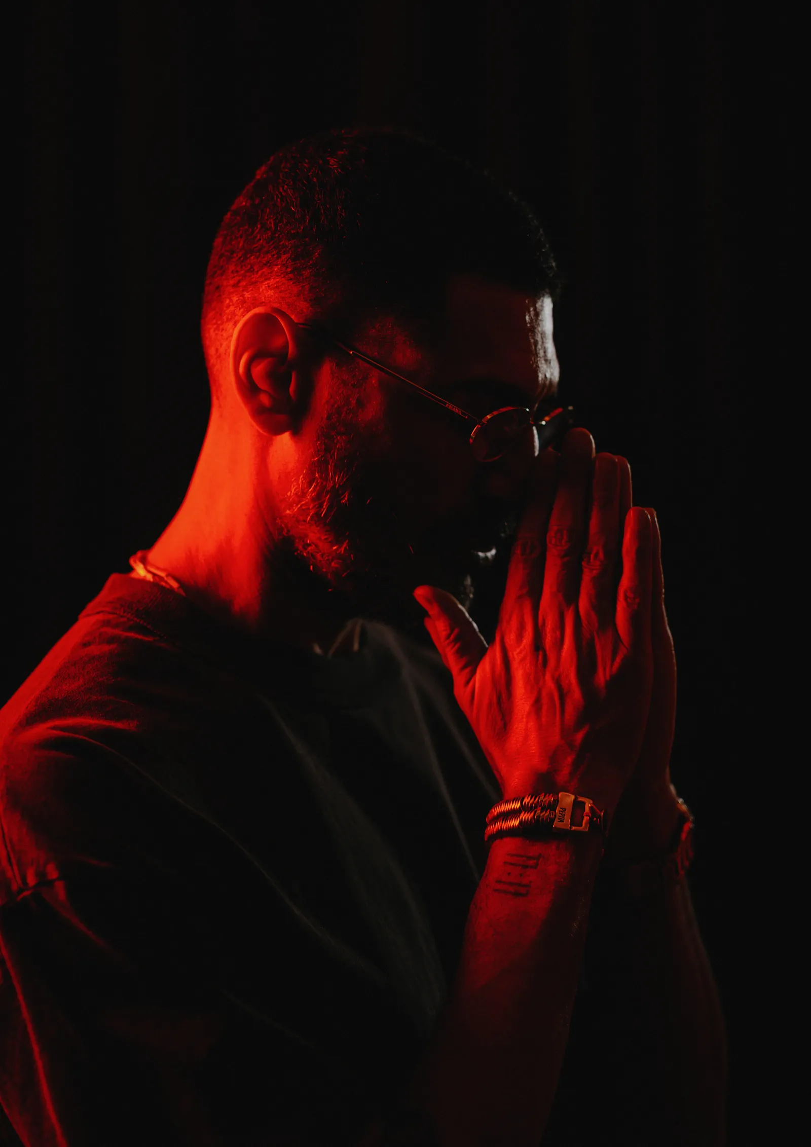 Criolo com as mãos unidas, luz vermelha