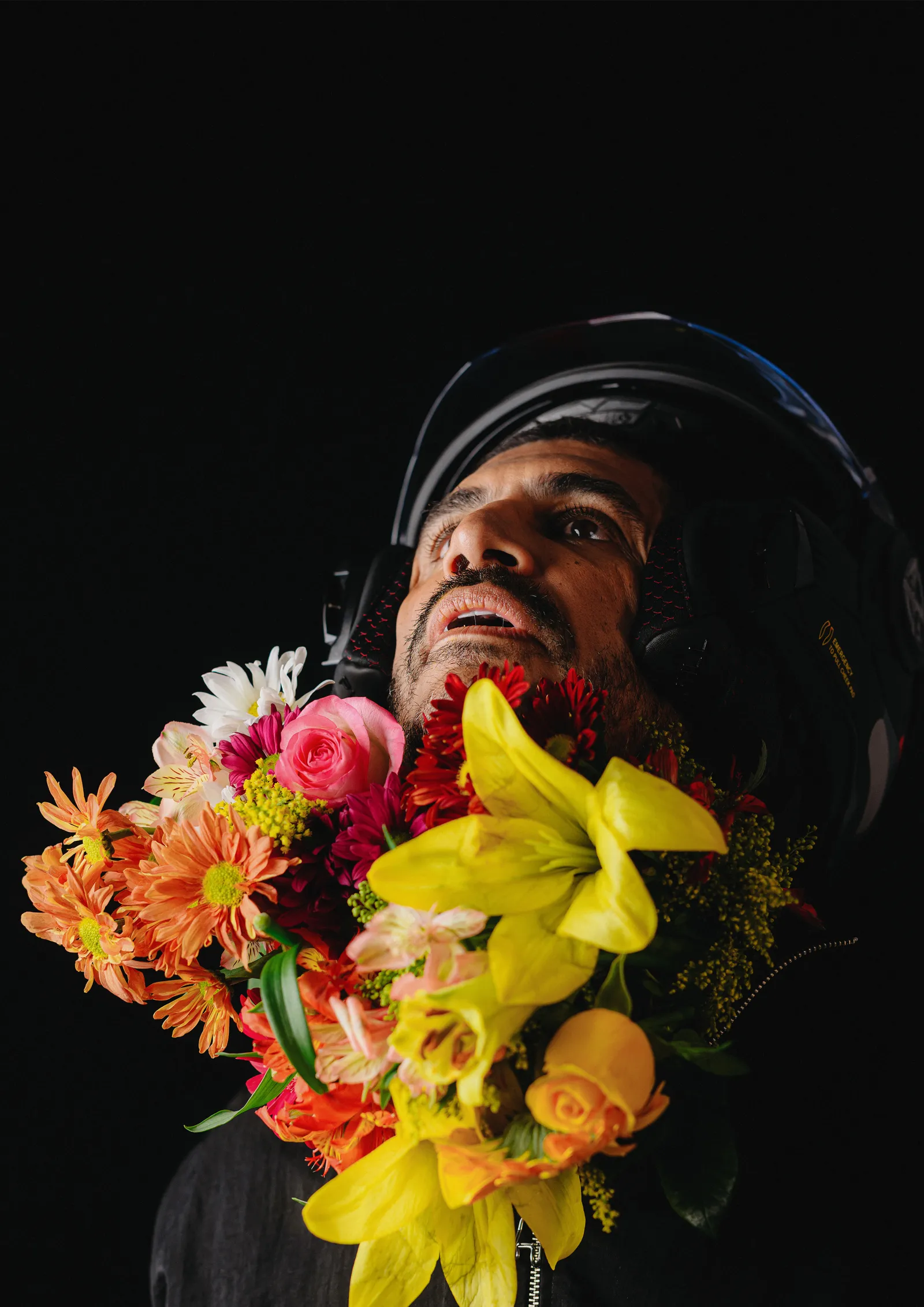 Criolo de capacete olhando para cima, cercado de flores